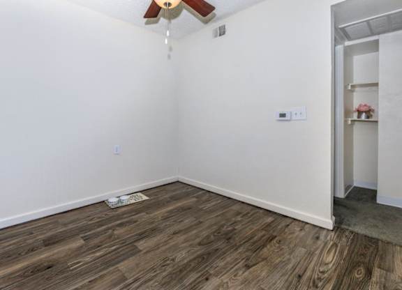A room with a ceiling fan and wooden flooring.