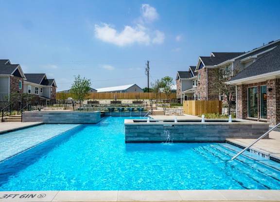 A swimming pool in a residential area with houses in the background.