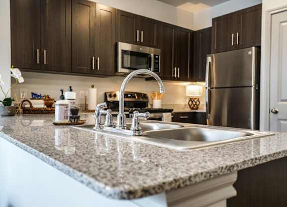 A kitchen with a granite countertop and stainless steel appliances.