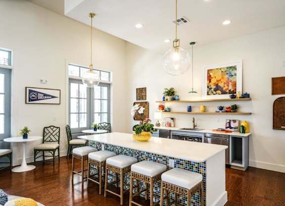 A kitchen with a white island and blue chairs.