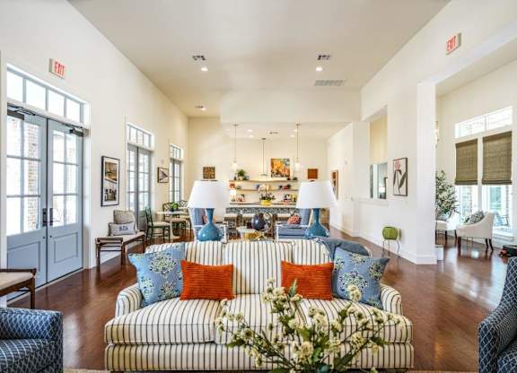 A living room with a striped couch and a vase of flowers on it.