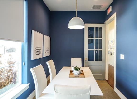 A dining room with a white table and chairs.