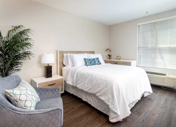 A bedroom with a bed, nightstand, and chair.