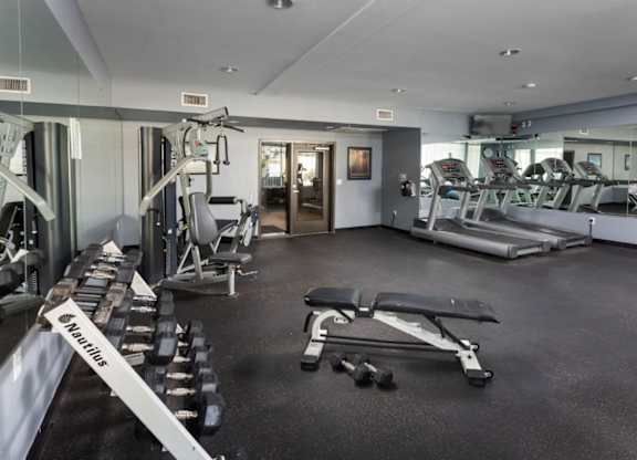 A gym with a variety of equipment including treadmills, weights, and exercise machines.