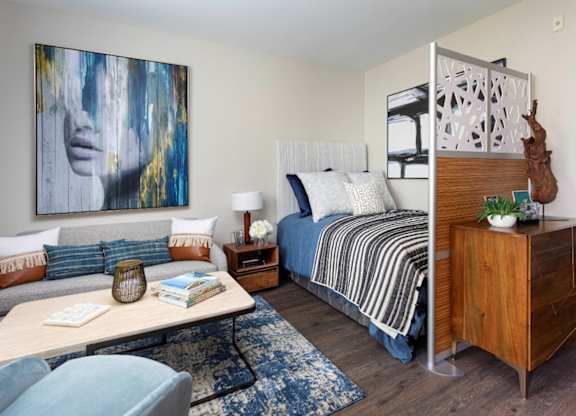A bedroom with a bed, nightstand, and a painting on the wall.