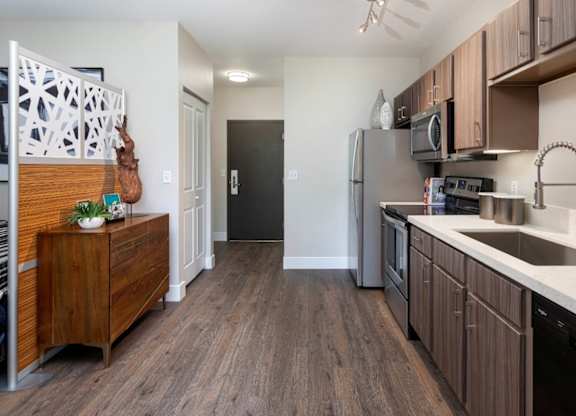 A kitchen with wooden floors and a black refrigerator.