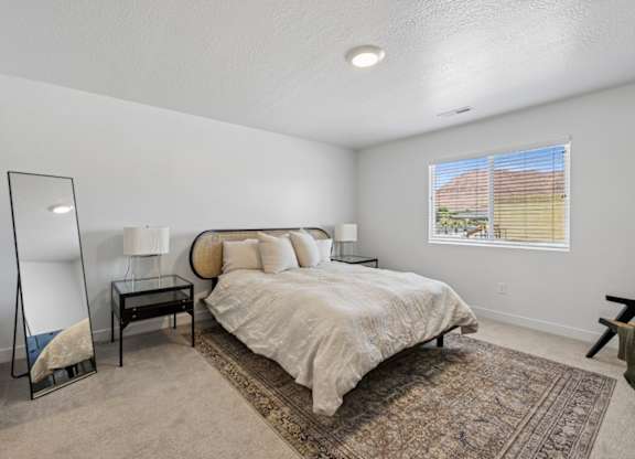 A bedroom with a bed, nightstand, and a mirror.