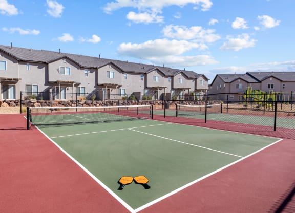 a tennis court with apartments in the background