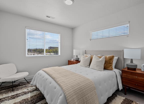 a bedroom with a large bed and two windows