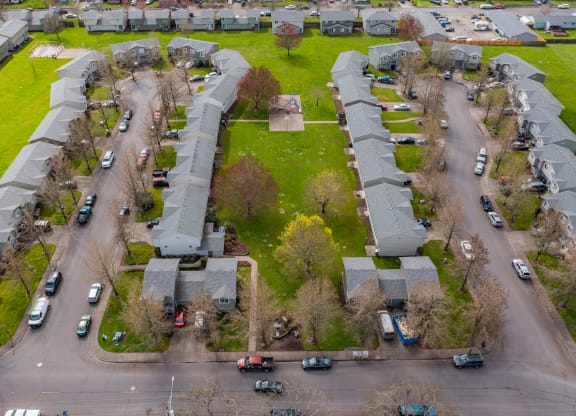 an aerial view of a neighborhood with green grass and cars parked on the street