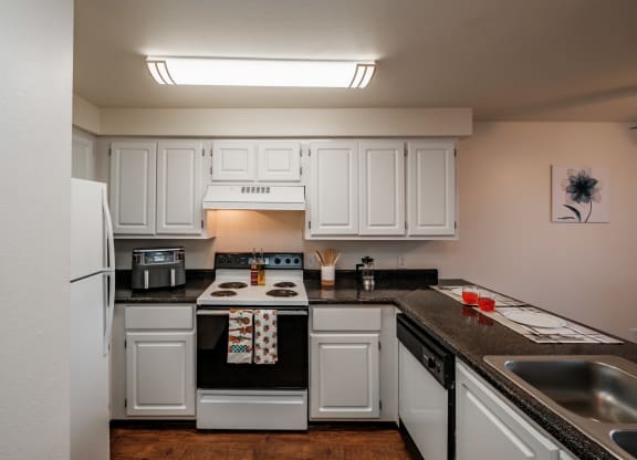 a kitchen with white cabinets and black countertops