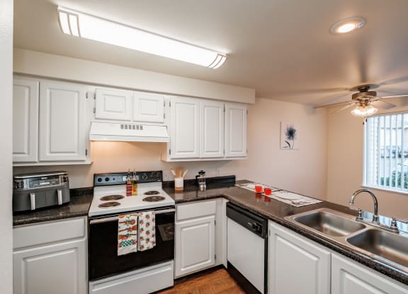 a kitchen with white cabinets and black countertops