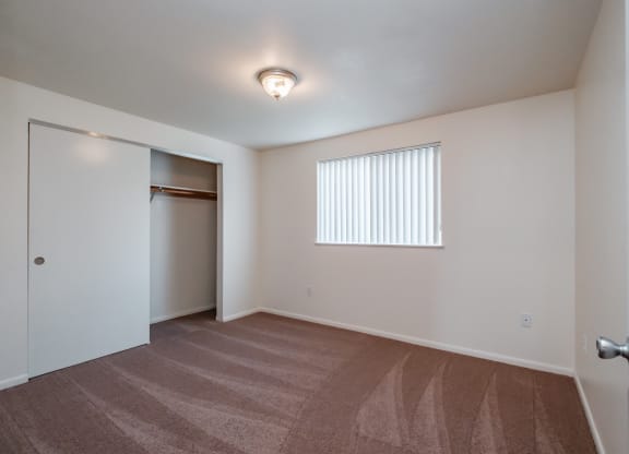 a bedroom with a door to a closet and a window