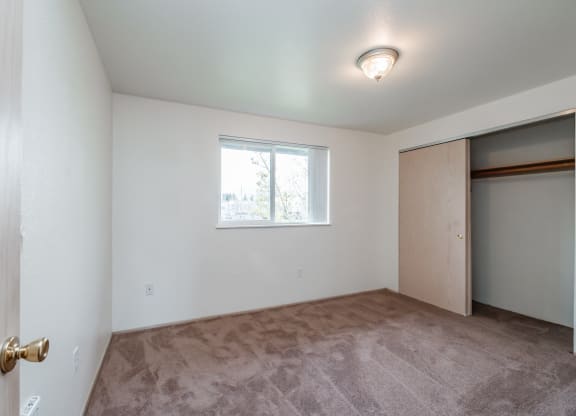 a bedroom with a large window and a closet