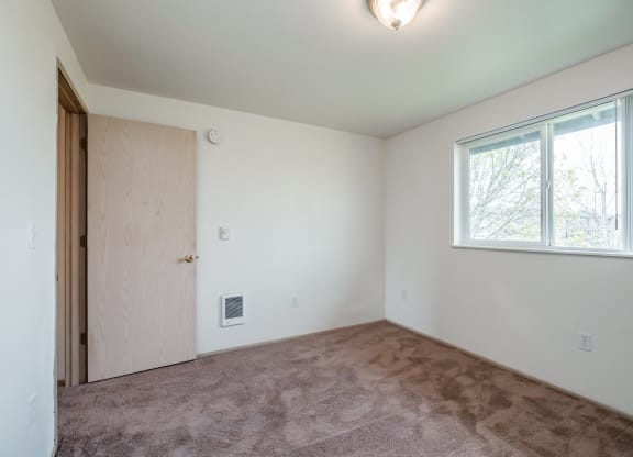 a bedroom with a carpeted floor and a large window