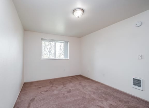 a bedroom with white walls and a window