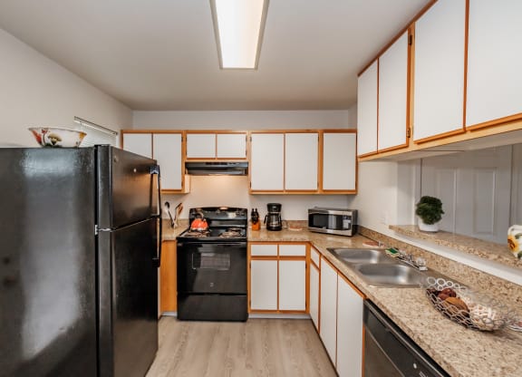 a kitchen with white cabinets and black appliances
