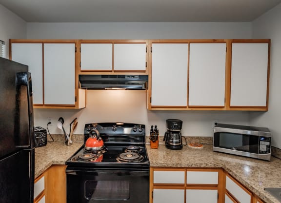 a kitchen with white cabinets and black appliances