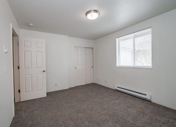 an empty bedroom with carpet and a window