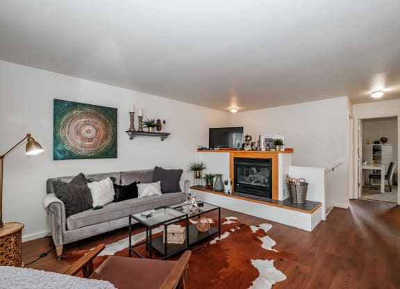 a living room with white walls and hardwood floors and a fireplace with a wooden mantel