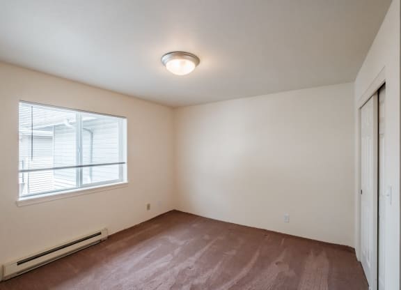 an empty bedroom with a large window and a closet