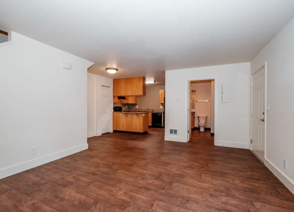a living room with a hardwood floor and a kitchen in the background