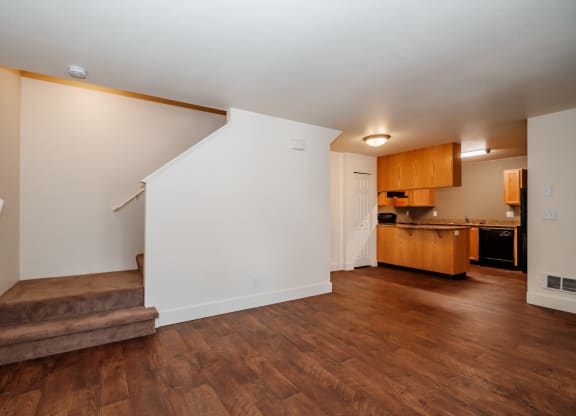 a living room with a staircase and a kitchen in the background