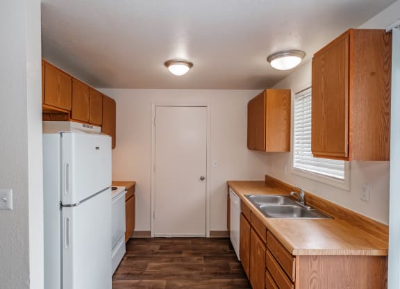 a kitchen with a white refrigerator freezer next to a sink and a window