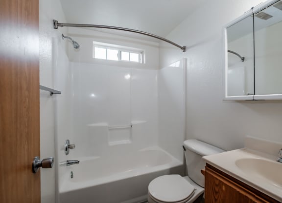 a bathroom with a white bathtub and toilet next to a sink and a mirror