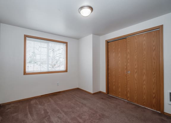 an empty bedroom with a large window and a wooden door