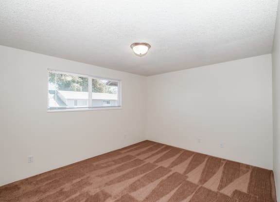a bedroom with white walls and a window
