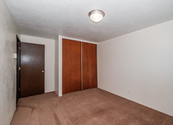a bedroom with a carpeted floor and a door to a closet