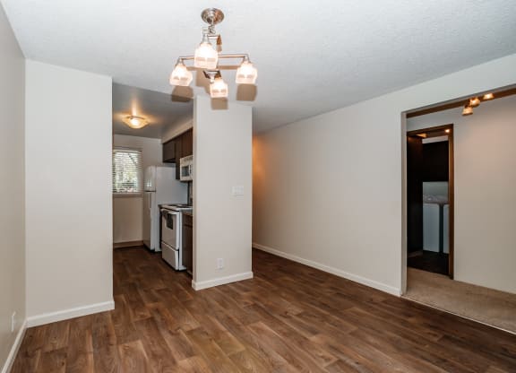 a living room with hardwood floors and a kitchen in the background