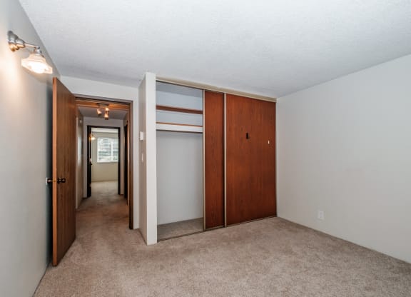 a bedroom with a carpeted floor and a closet with a mirrored door