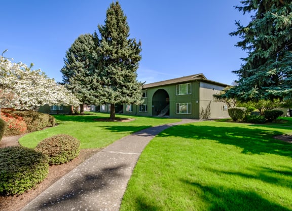 a home with a green exterior and manicured lawns