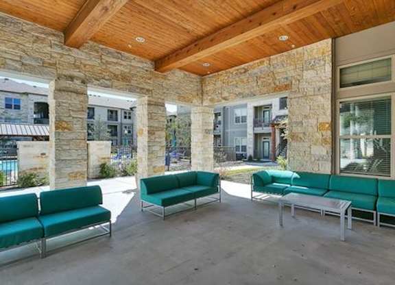 A patio with a green couch and a wooden ceiling.