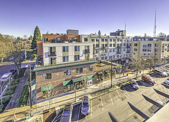 A parking lot with cars and a building with a green awning in the background.