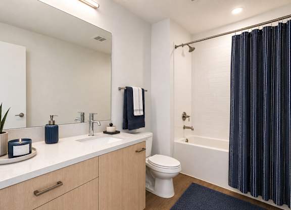 A bathroom with a toilet, sink, mirror, and shower curtain.