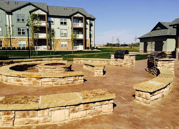 A large stone patio with a fire pit in the middle.