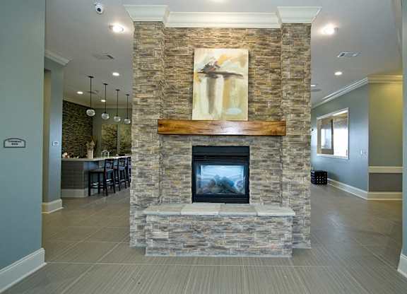 A stone fireplace with a painting above it in a room.