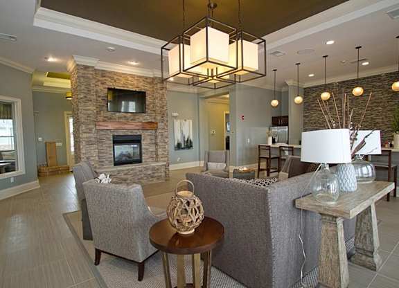A living room with a grey couch, a stone fireplace, and a wooden coffee table.