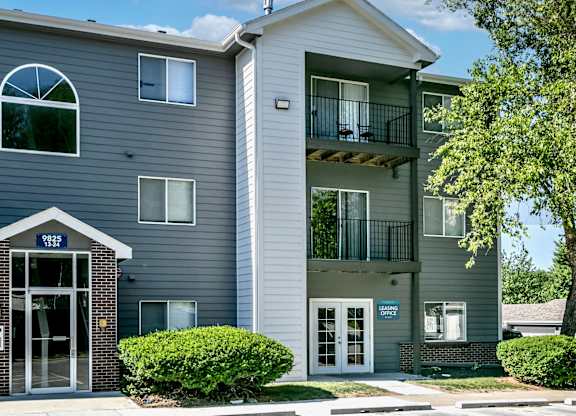 A grey apartment building with a balcony on the second floor.
