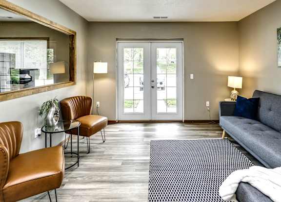 A living room with a grey couch, two chairs, and a rug.