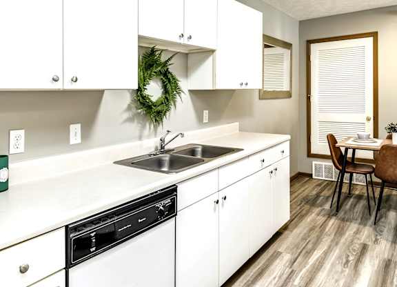 A kitchen with white cabinets and a wreath on the wall.
