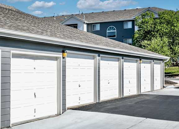 A row of white garage doors in front of a house.
