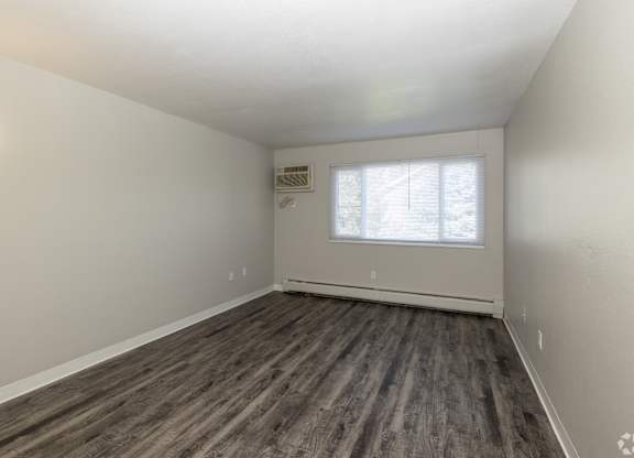 A room with a window and a wooden floor.