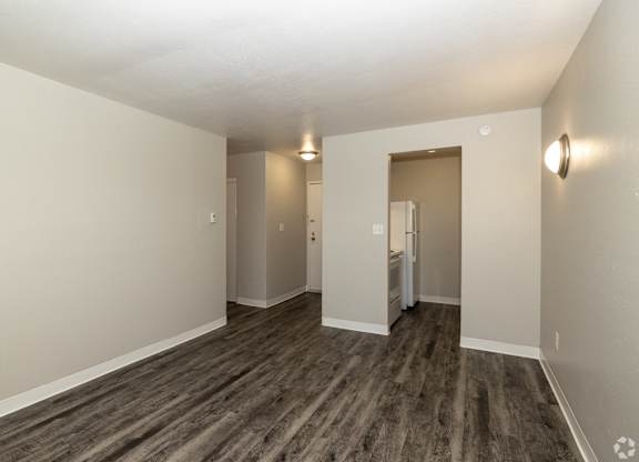 A room with a wooden floor and a doorway leading to another room.