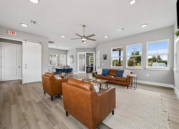 A living room with a brown leather couch and a ceiling fan.