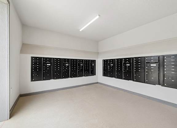 A room with a white ceiling and a row of black lockers on the wall.