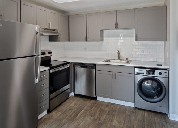 a kitchen with gray cabinets and stainless steel appliances